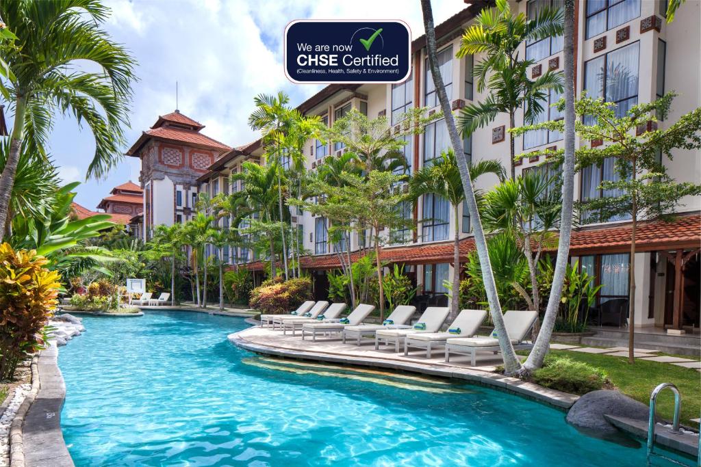 沙努尔巴厘岛总理大酒店 - 巴厘岛的一座游泳池,里面摆放着椅子和棕榈树