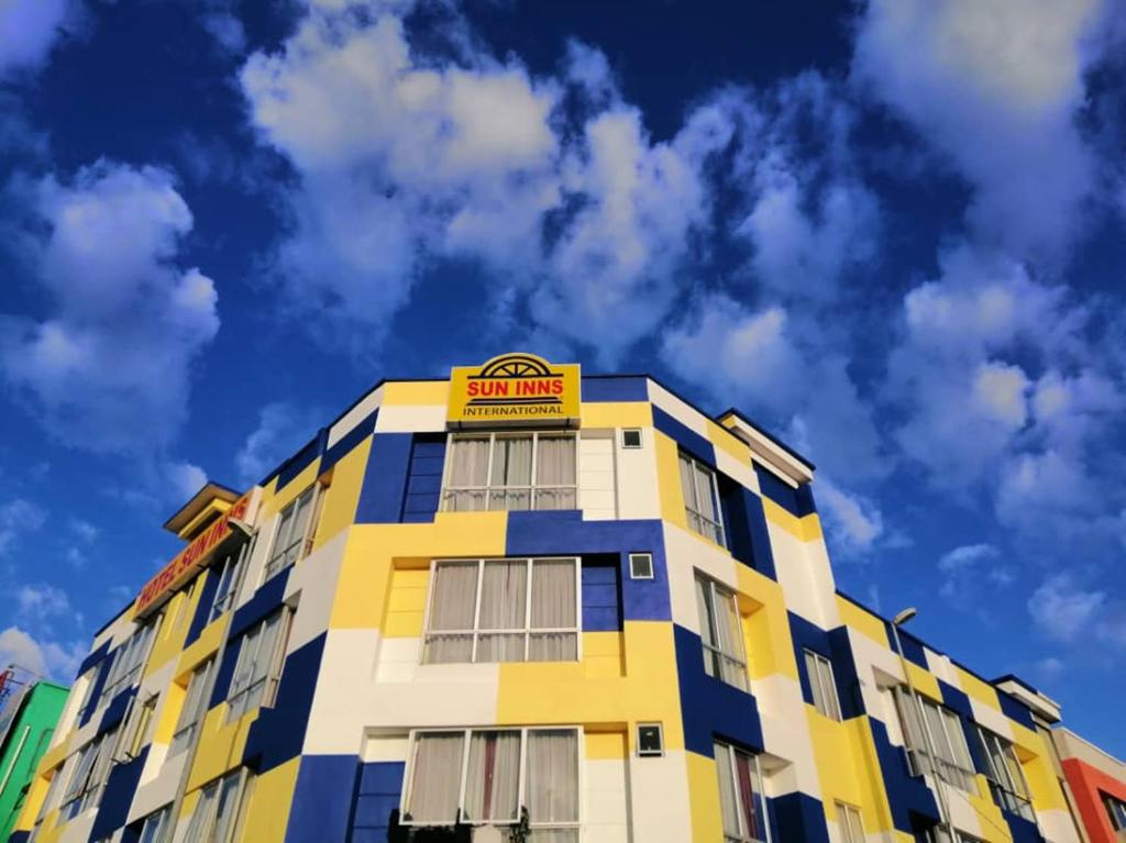 ChemorSun Inns Hotel Meru Raya的黄色和蓝色的建筑,上面有标志