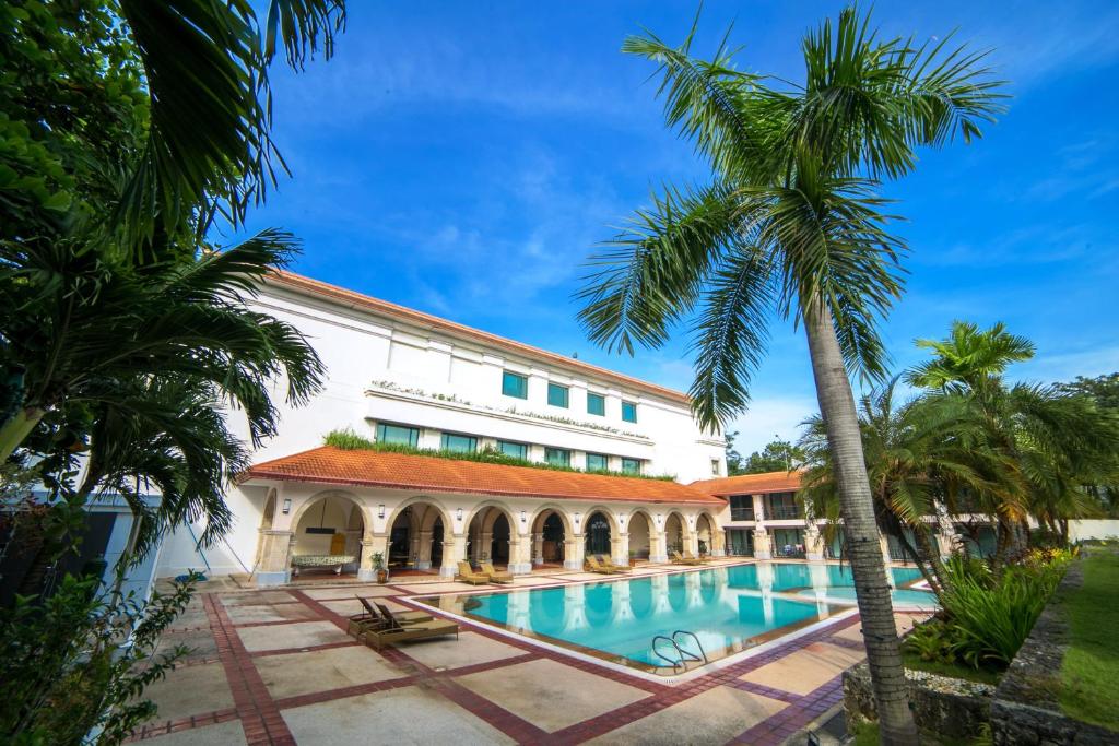 麦克坦Waterfront Airport Hotel and Casino的一个带游泳池和棕榈树的度假村