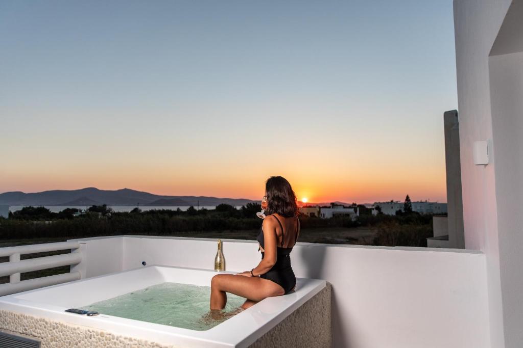 MaragkasVilla Gold & White的坐在浴缸里观看日落的女人