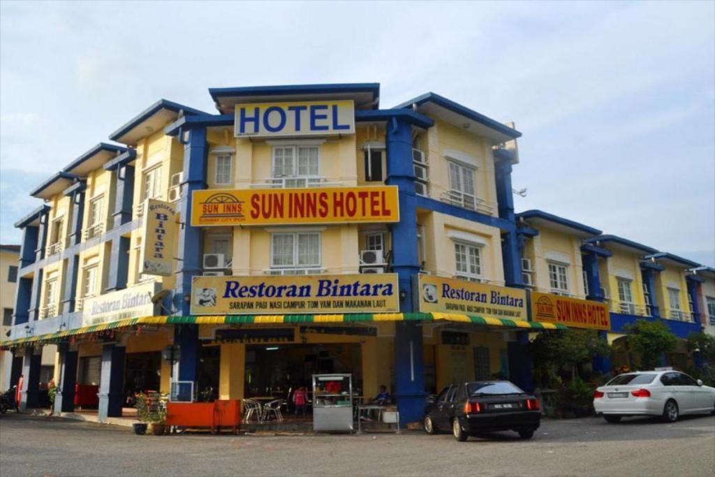 Kampong Batu LapanSun Inns Tambun的一条街道上的酒店,门前有车辆停放