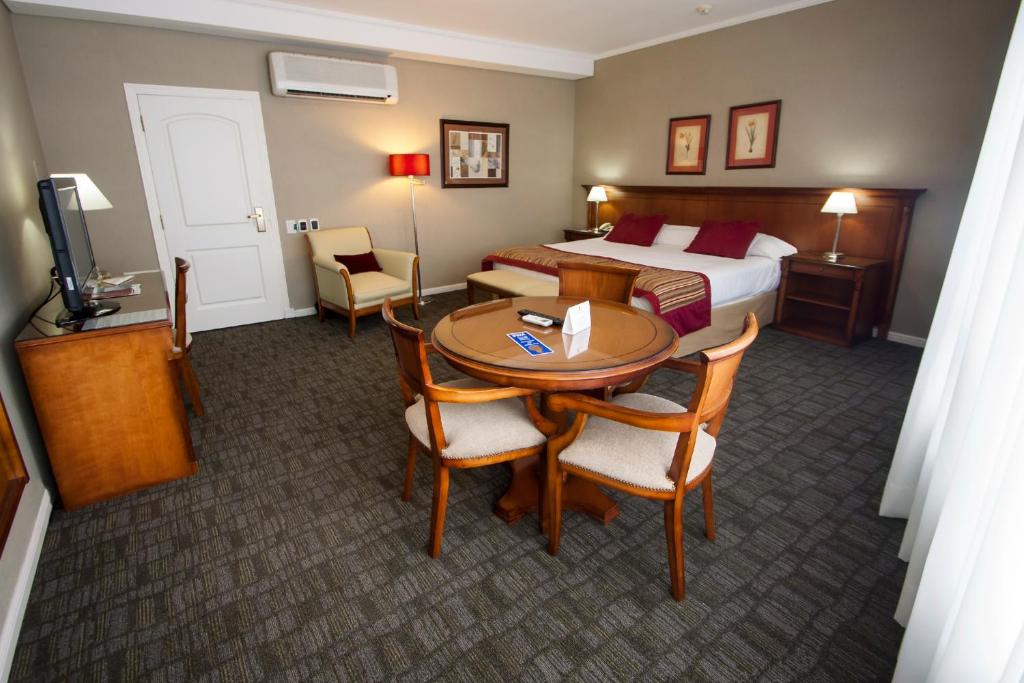 圣米格尔·德·图库玛图库曼中心商务套房酒店的酒店客房带一张床、一张桌子和椅子