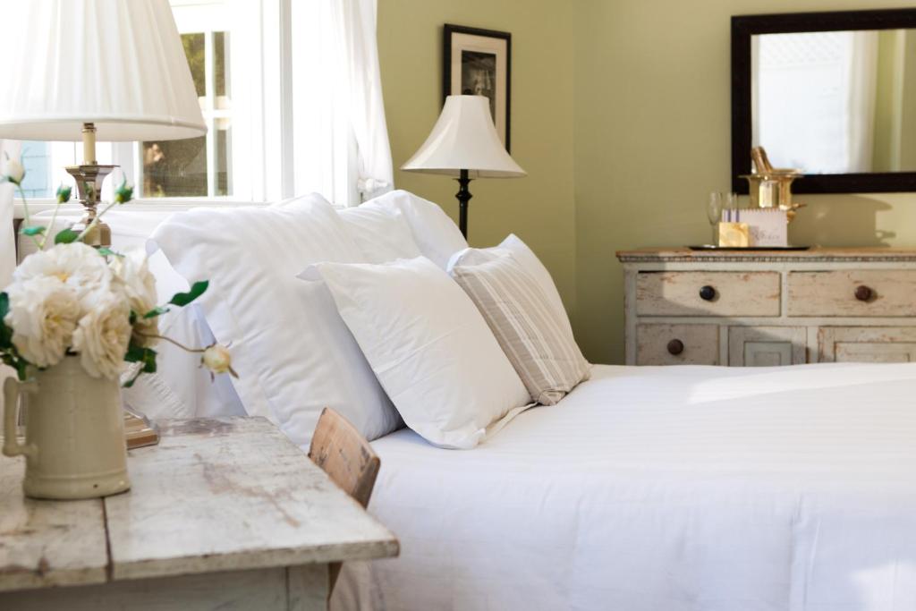 洛杉矶海岬路旅馆－四姐妹酒店的卧室配有带白色枕头和桌子的床