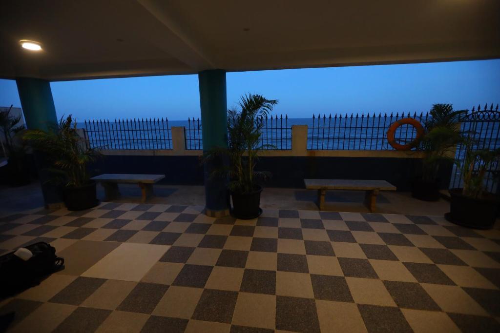 蓬蒂切里Lamel Cove Beach Resort的一间设有长椅和植物的 ⁇ 格地板的房间