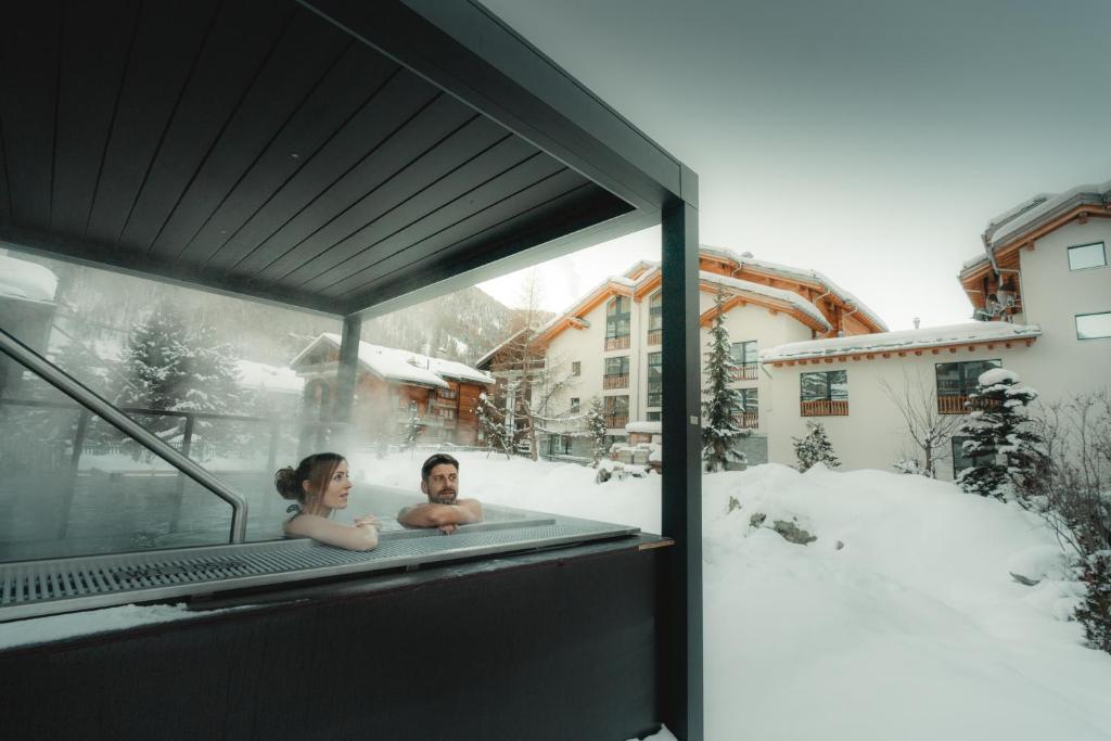 采尔马特采尔马特经济型酒店的男人和女人在雪中的浴缸里