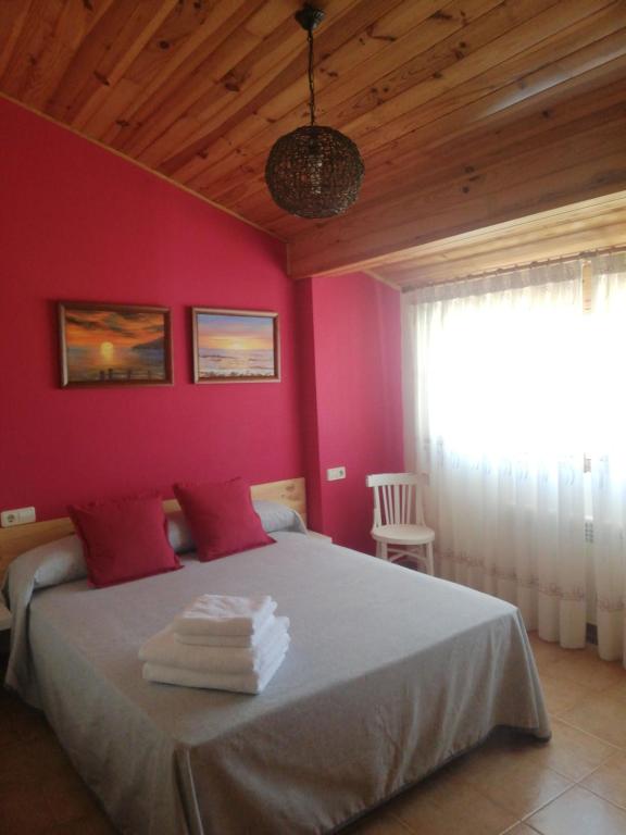 MontánCasa Rural Los Pineros的卧室配有一张带粉红色墙壁的大床