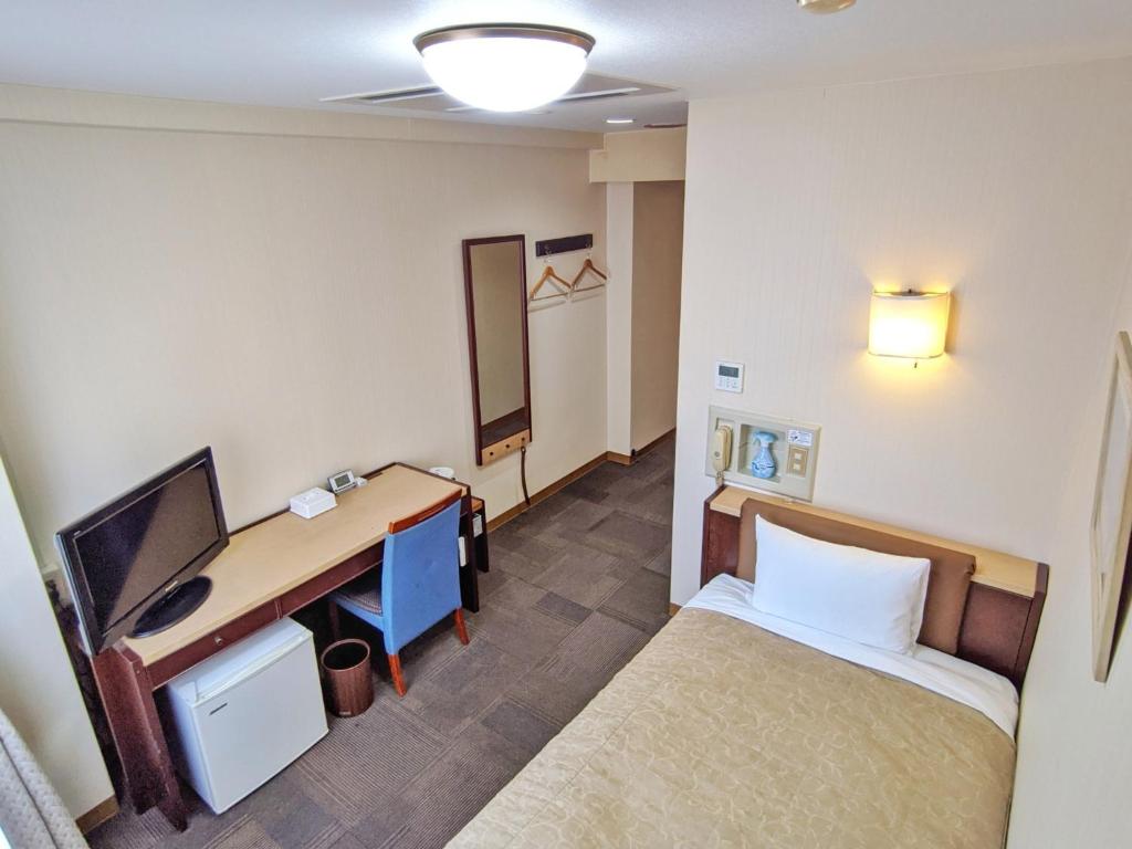 KadomaKadoma Public Hotel/ Vacation STAY 33571的客房设有一张床、一张桌子和一台电脑