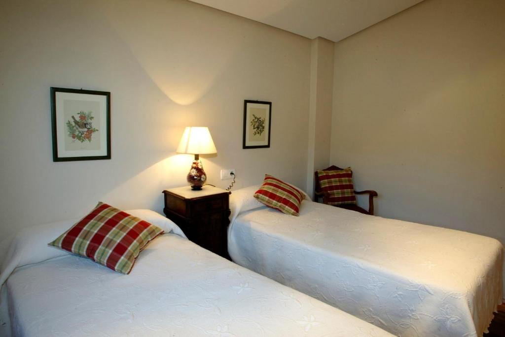 LuyandoURDINETXE的一间卧室设有两张床和一张桌子上的台灯。