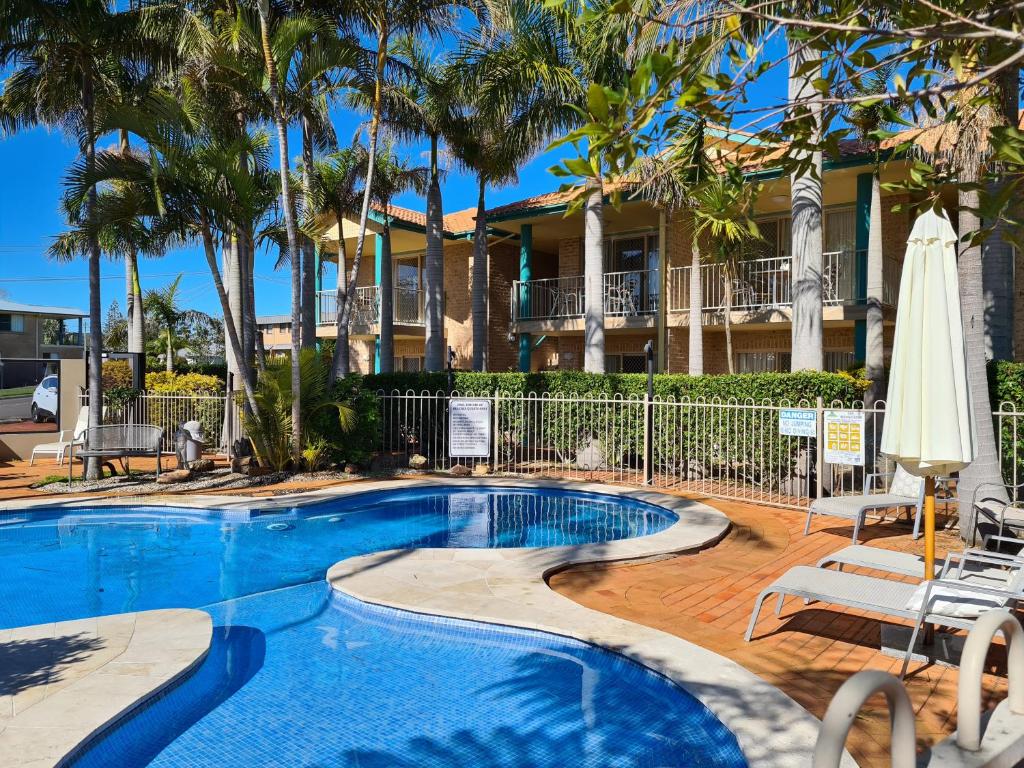 尼尔森湾海滩服务公寓的一座棕榈树游泳池和一座房子