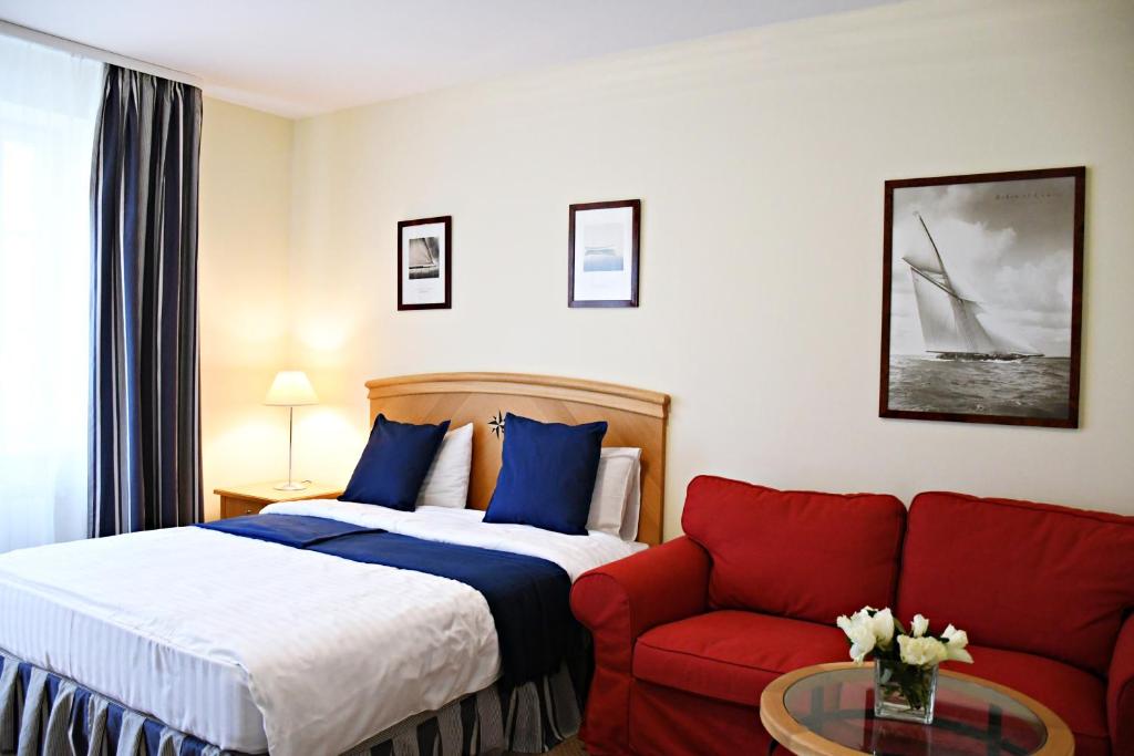 帕兰加Žalias namas的酒店客房,配有一张床和一张红色的沙发