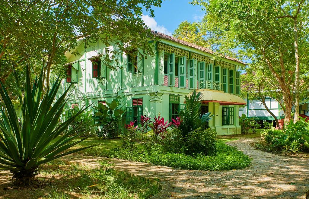 珍南海滩Temple Tree Resort的一座绿色建筑,前面有树木和植物