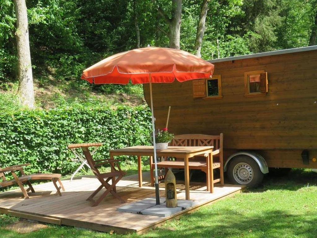 WildbergBienenwagen der Naturheilpraxis Melchger的拖车旁带雨伞的桌子