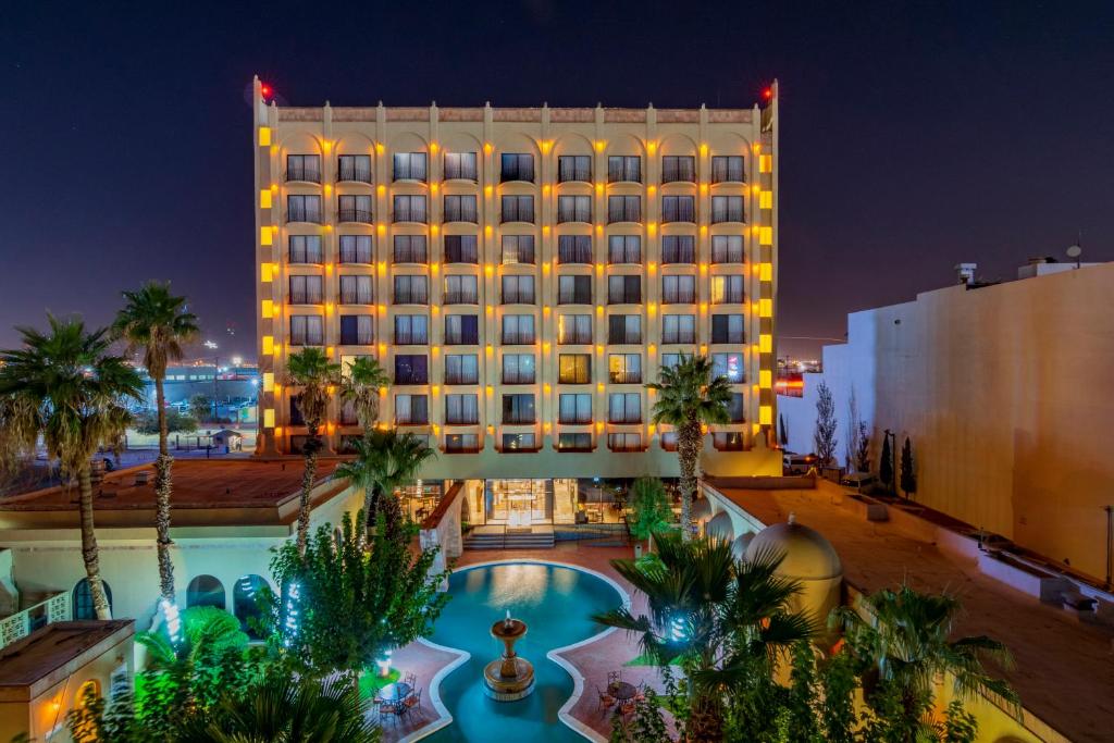华雷斯城华雷斯城卢鲁斯那酒店的夜间有游泳池和棕榈树的酒店