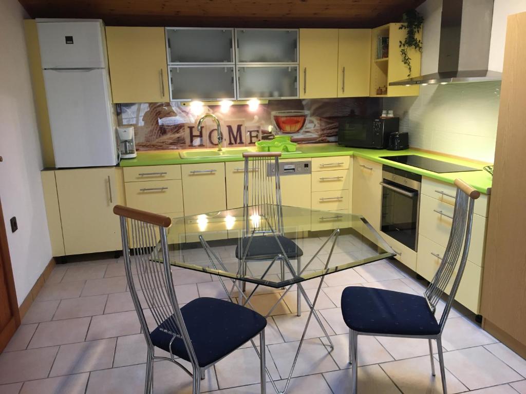 西格利盖特Horváth Apartmanház的厨房配有玻璃桌和两把椅子