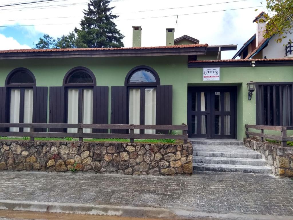 蒙特韦尔迪Pousada Vênus的一座带石墙的绿色房子