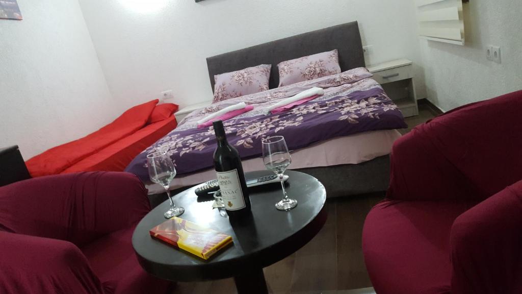 波德戈里察Apartments F的一间设有床铺和一张桌子及酒杯的房间