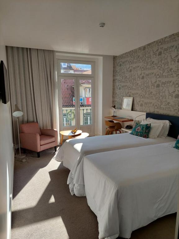里斯本奥古斯塔精品住宿加早餐旅馆的卧室配有一张白色大床和一把椅子