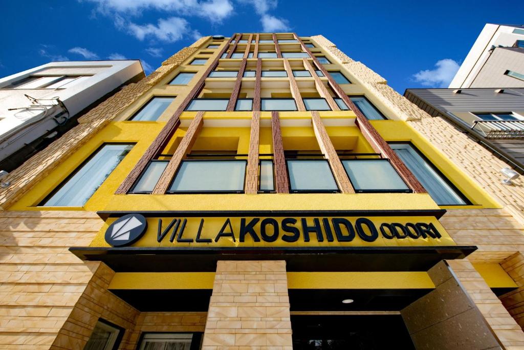 札幌VILLA KOSHIDO ODORI的黄色的建筑,前面有标志