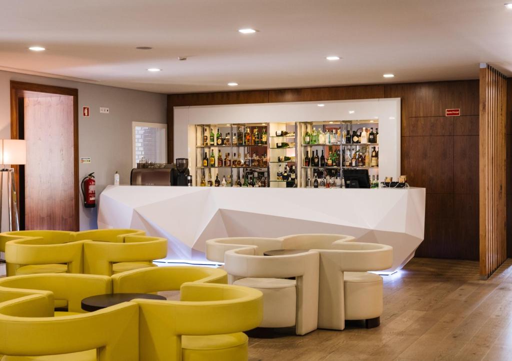 蓬蒂-达巴尔卡Hotel Fonte Velha的酒吧设有黄色椅子和白色柜台