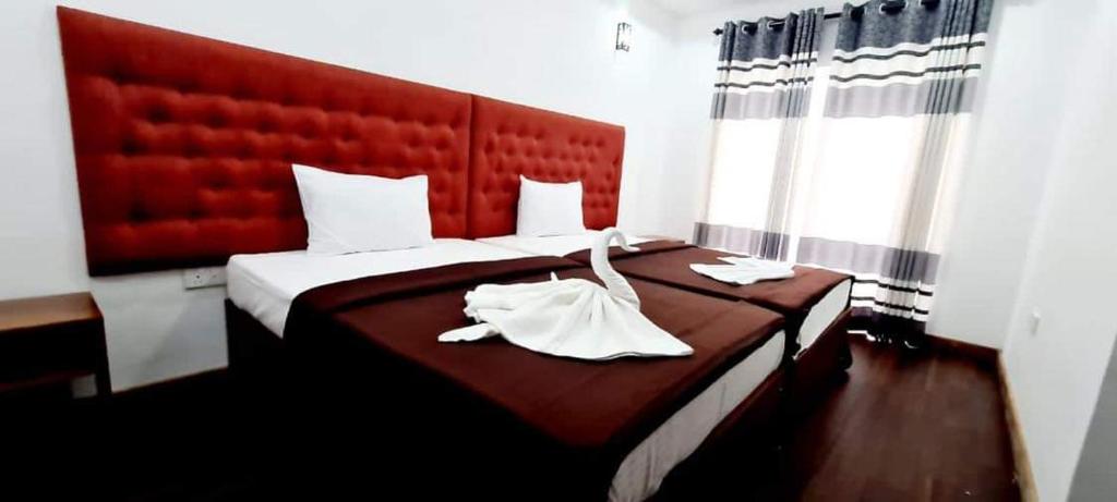 努沃勒埃利耶Nive Inn的一间卧室配有一张大床和红色床头板