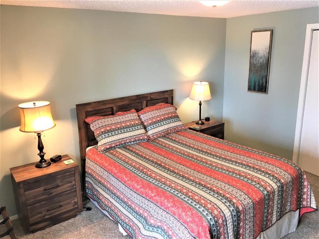 拉皮德城Priceless Black Hills View的一间卧室配有一张带色彩缤纷的床罩和两盏灯的卧室