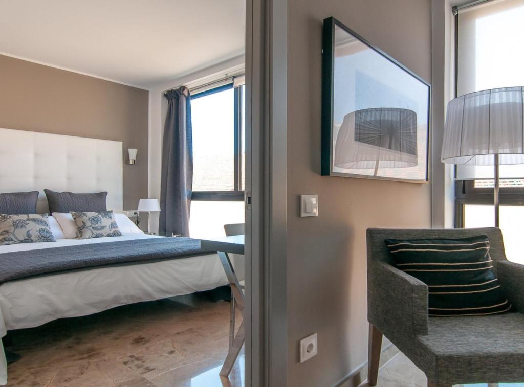 巴塞罗那Picasso Suites 5.1 Paseo de Gracia的一间卧室配有一张床、一把椅子和窗户。