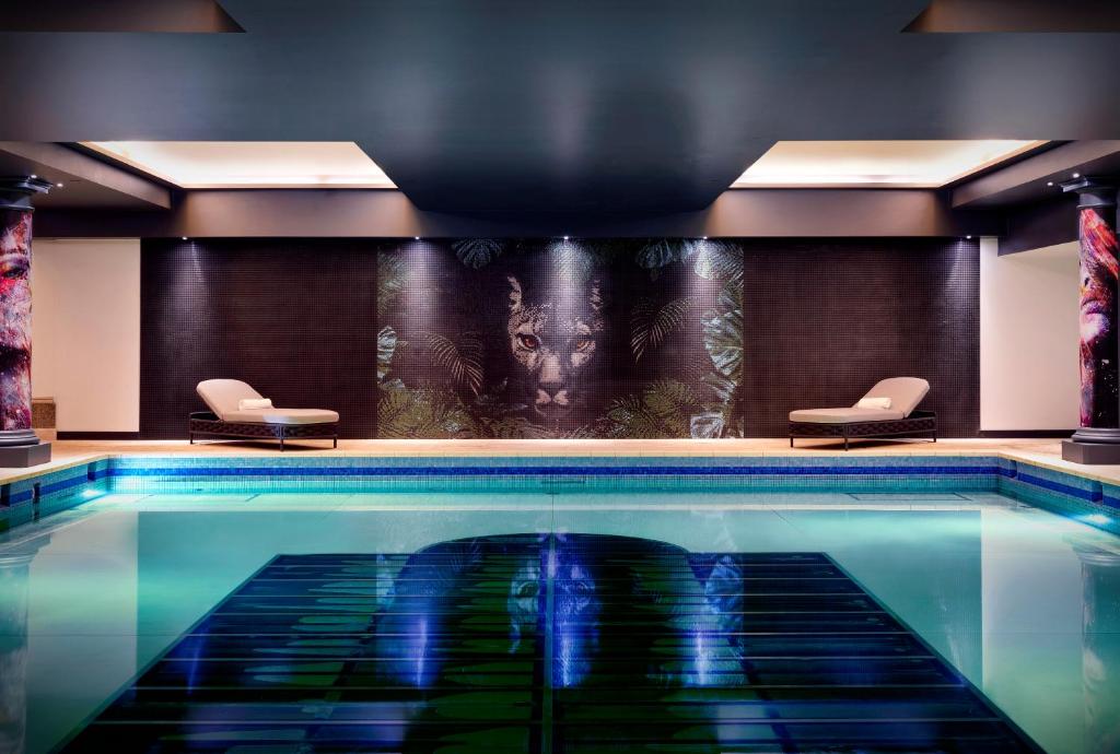 伦敦NYX Hotel London Holborn by Leonardo Hotels的一个带两把椅子的酒店客房的游泳池