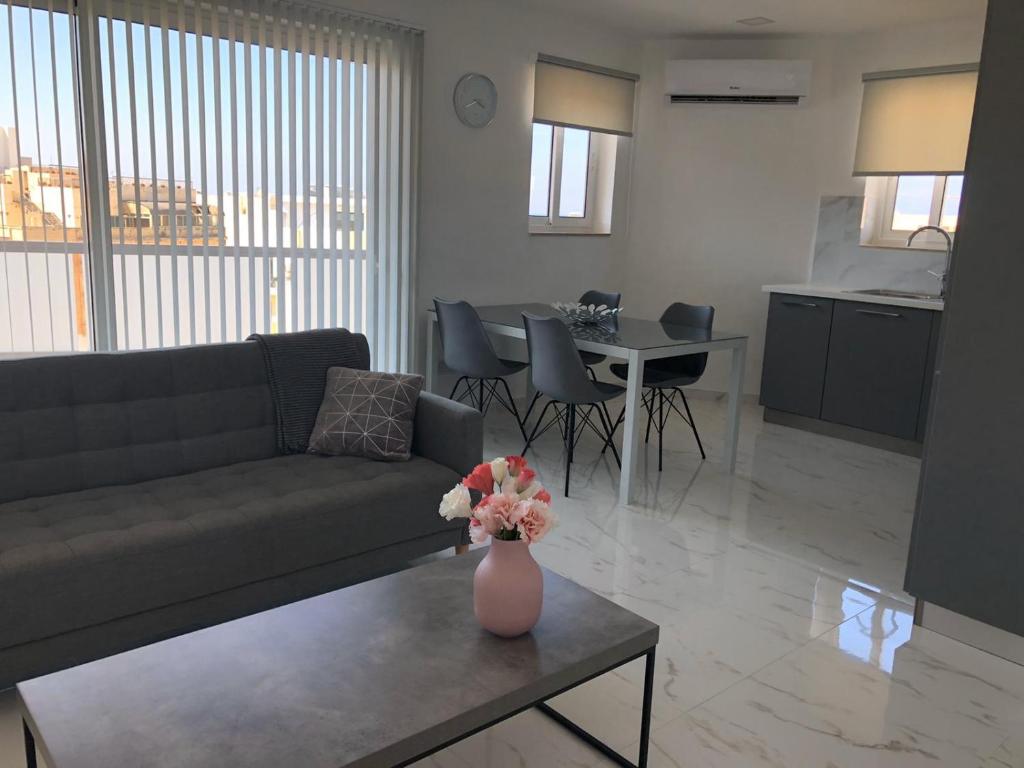 圣保罗湾城Bugibba Sunrise View Modern Apartment的客厅配有沙发和花瓶(桌子上)
