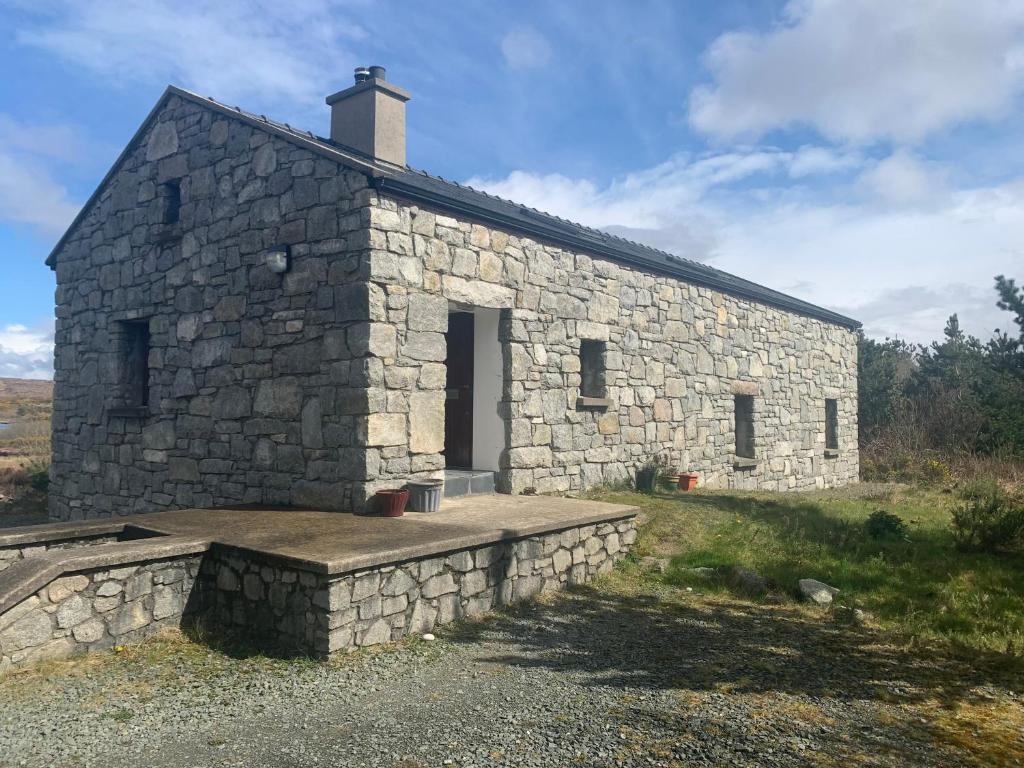 邓格洛Lough Meela Lodge的一块石头建筑,在田野上有一扇门