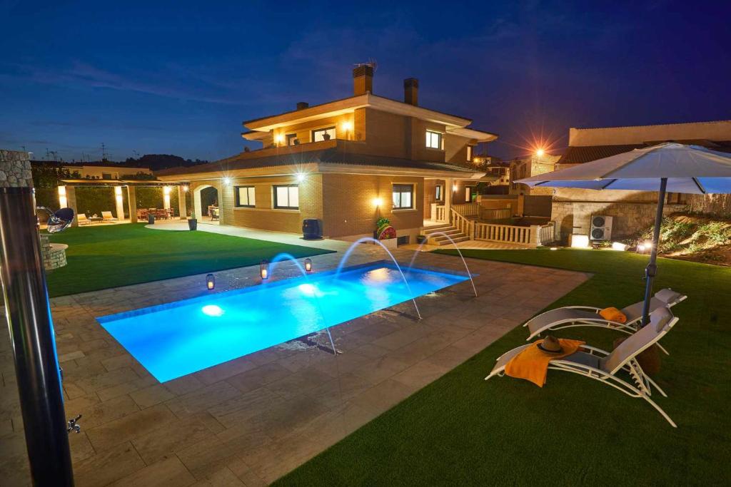 ViñaixaLa Cantera Rural Spa的一座房子,晚上在院子里设有一个游泳池