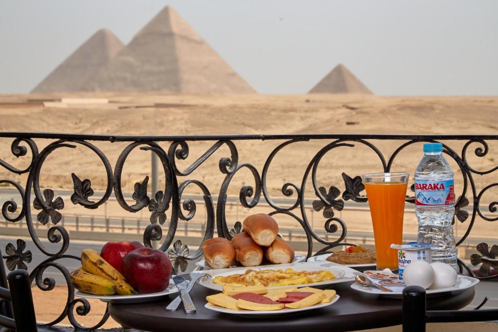 开罗Pyramids Planet Hotel的餐桌,餐桌上放有食物和饮料盘,金字塔