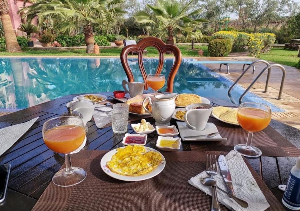 BerrechidEqui Palace & SPA Near Aeroport的一张桌子,旁边是游泳池,提供早餐食品和饮料