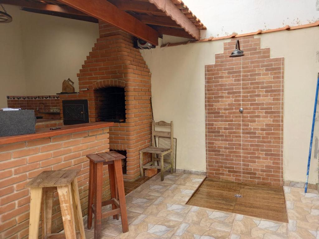 伊利亚孔普里达Casa Azul no Centro Ilha Comprida的一间客房内的砖砌壁炉,配有两张凳子