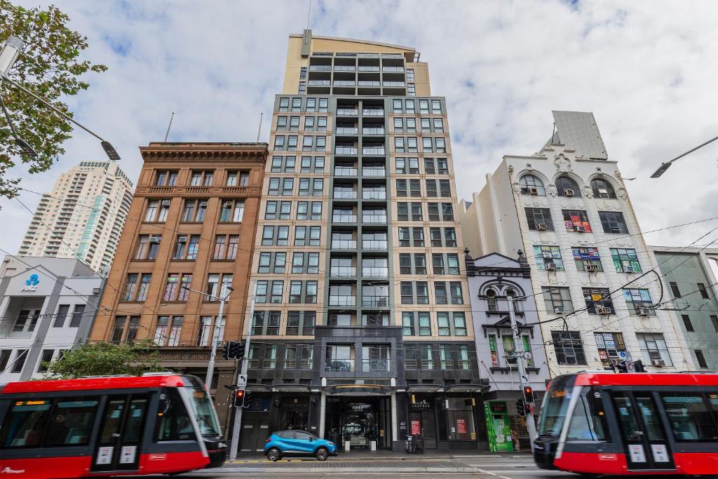悉尼Mantra Sydney Central的一座城市,在高楼前有两辆公共汽车