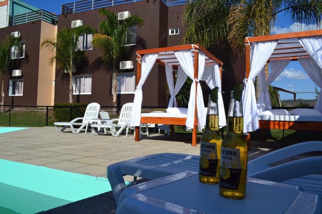 维拉卡洛斯帕兹Hotel Montana by CPH的两瓶啤酒坐在泳池旁的桌子上