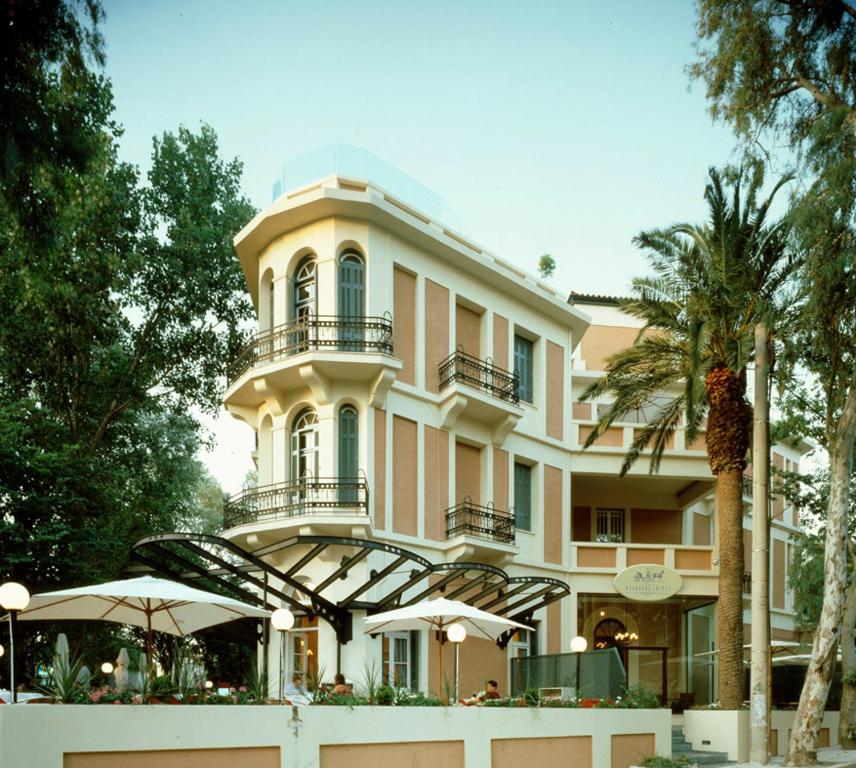 雅典The Kefalari Suites的一座大建筑,前面设有阳台和遮阳伞