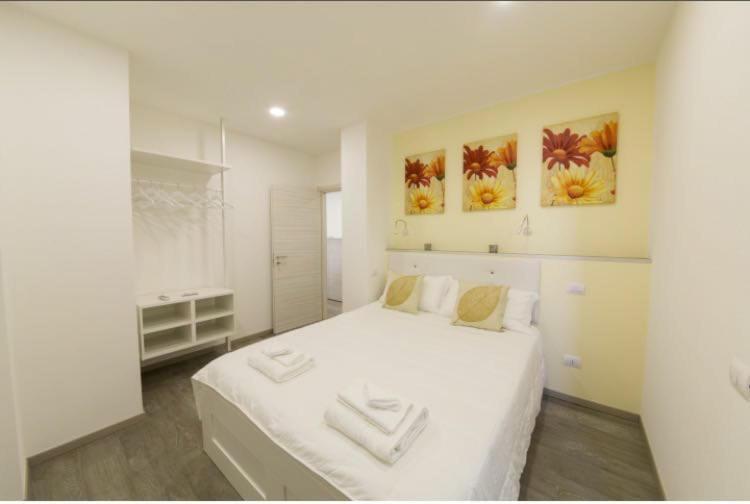 卡利亚里Sorores Bed&Breakfast的一间白色卧室,配有一张白色的大床和两幅画作