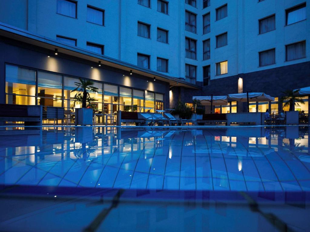 卡尔达诺阿尔坎波诺富特米兰马尔彭萨机场酒店的夜间在大楼前的游泳池