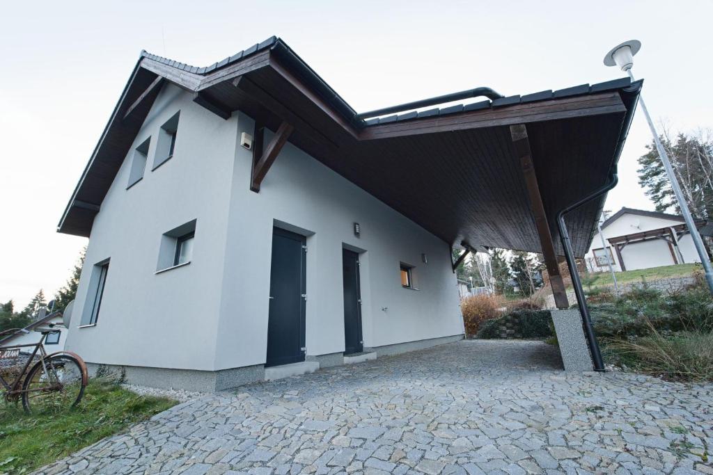 伏尔塔瓦河畔利普诺Holiday Lipno的一间小型白色房屋,设有太阳能屋顶