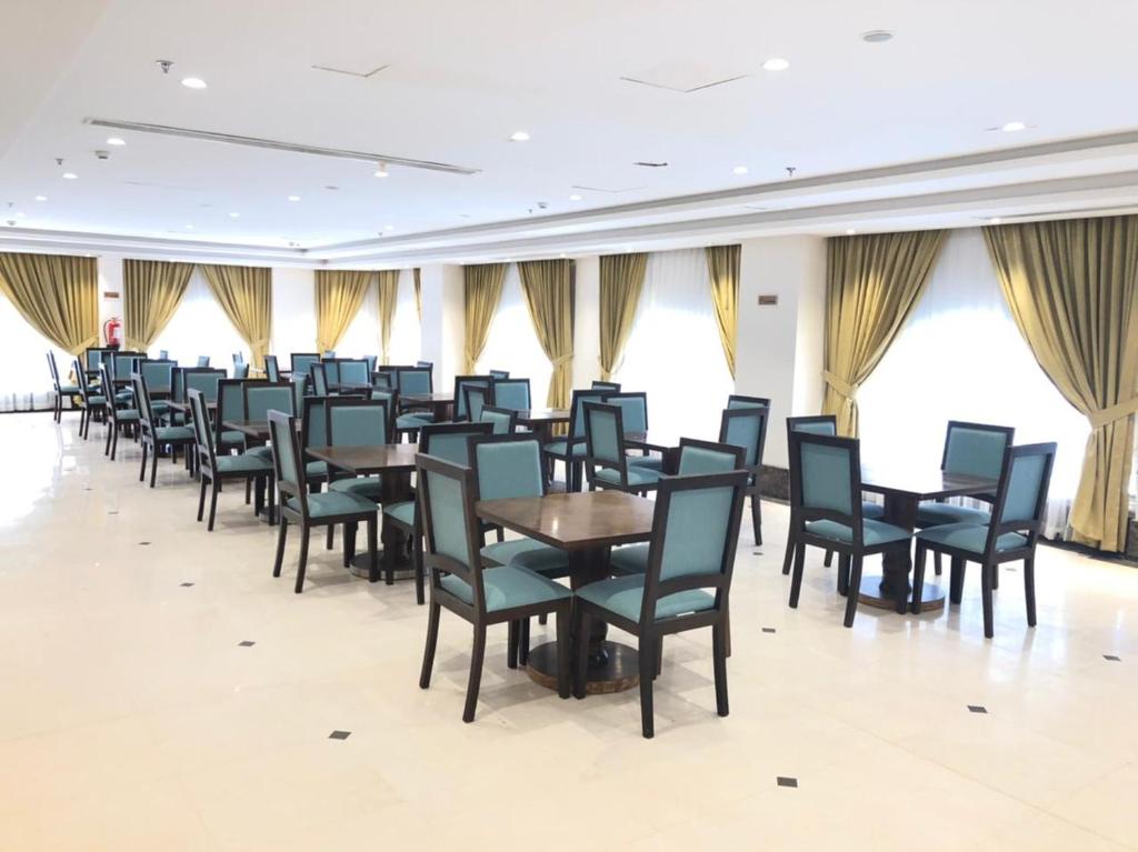 麦地那Zaha Al Madina Hotel的用餐室设有桌椅和窗户。