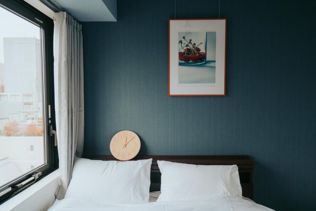东京unito SHIODOME的卧室配有一张挂在墙上的带时钟的床