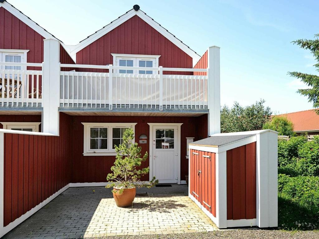 布拉万德4 person holiday home in Bl vand的红色的房子,上面有一个白色阳台