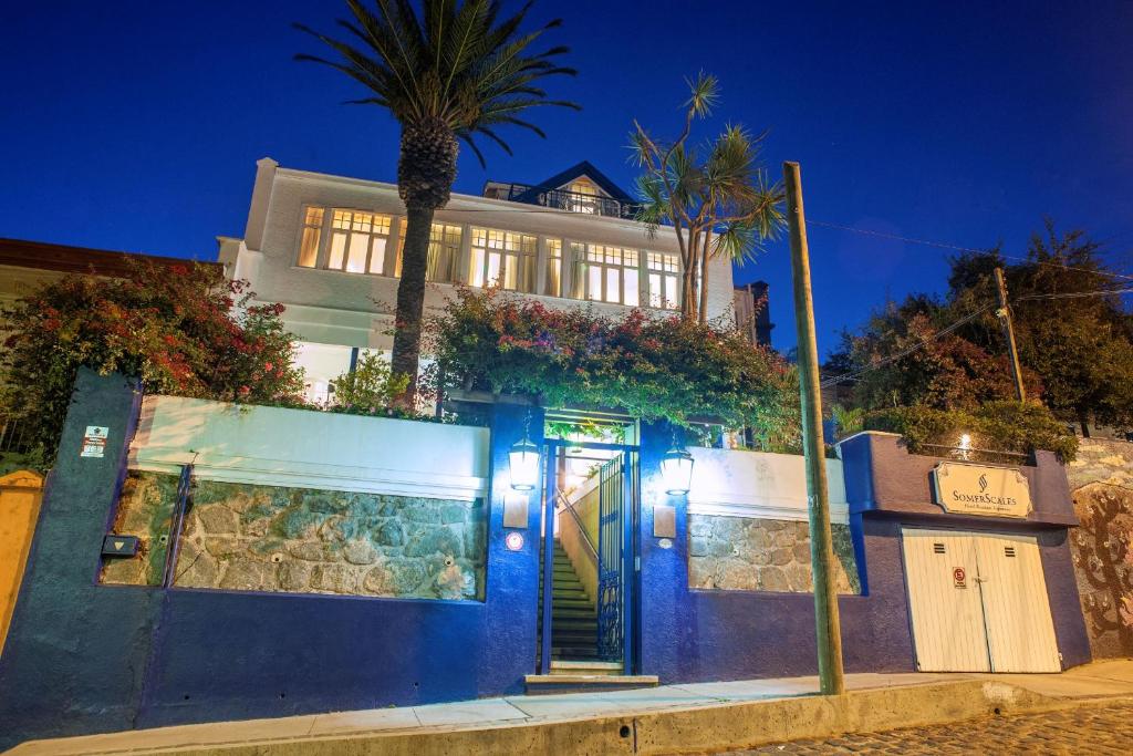 瓦尔帕莱索Hotel Casa SOMERSCALES的一座带蓝色门和棕榈树的房子