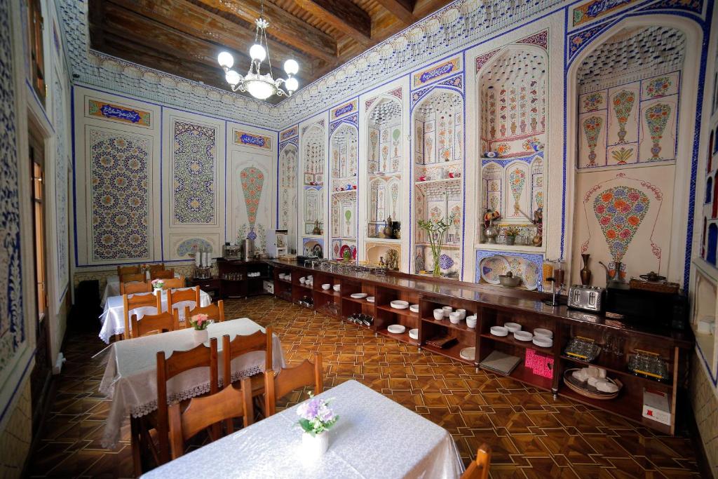 布哈拉卡夫萨精品酒店的餐厅设有多彩的墙壁,配有桌椅