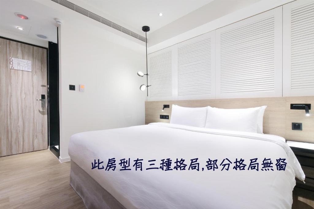 基隆集好旅店的卧室配有一张白色大床,上面写有中国字迹