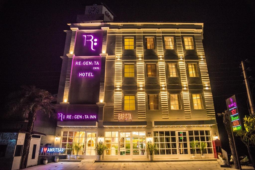 阿姆利则Regenta Inn Amristar Airport Road by Royal Orchid Hotels Limited的一座大建筑,晚上有紫色标志