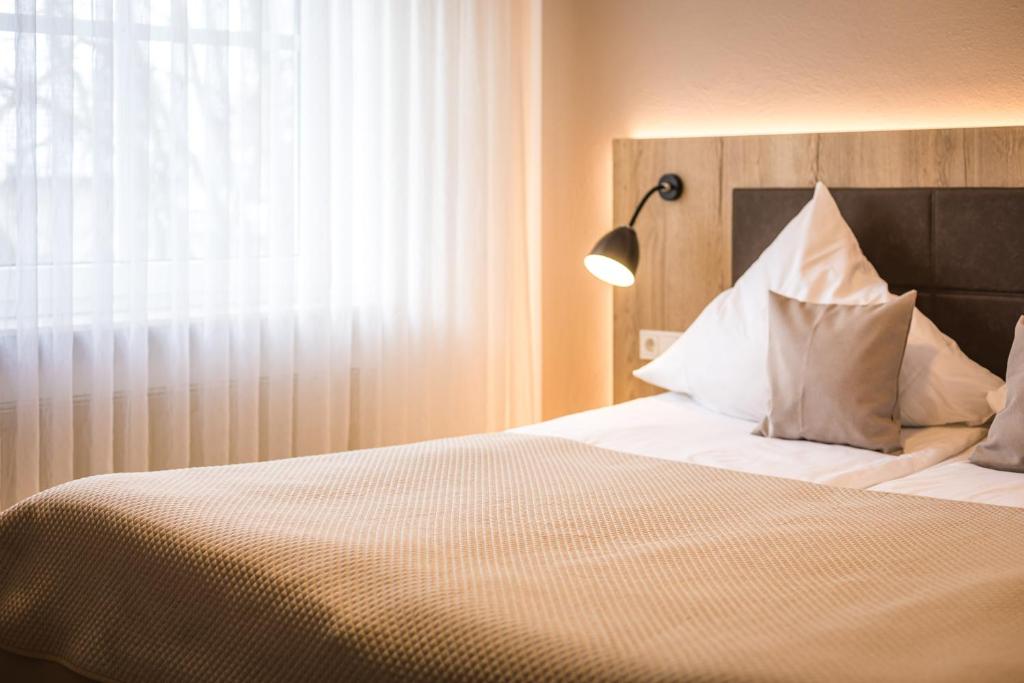 Nieder-SaulheimHotel Lehn的一间卧室配有带白色枕头和灯的床