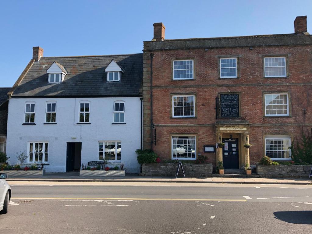 IlchesterThe Ilchester Arms Hotel, Ilchester Somerset的街道上一座大型砖砌建筑,前面有停车位