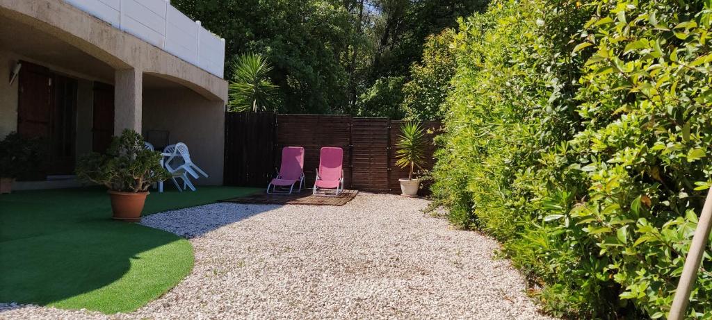 拉克罗Studio L'agasso Prouvenco的两把粉红色的椅子坐在围栏旁边的院子中