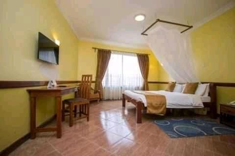 内罗毕Upper Hill Guest House Nairobi的一间卧室配有一张床、一张书桌和一个窗户。